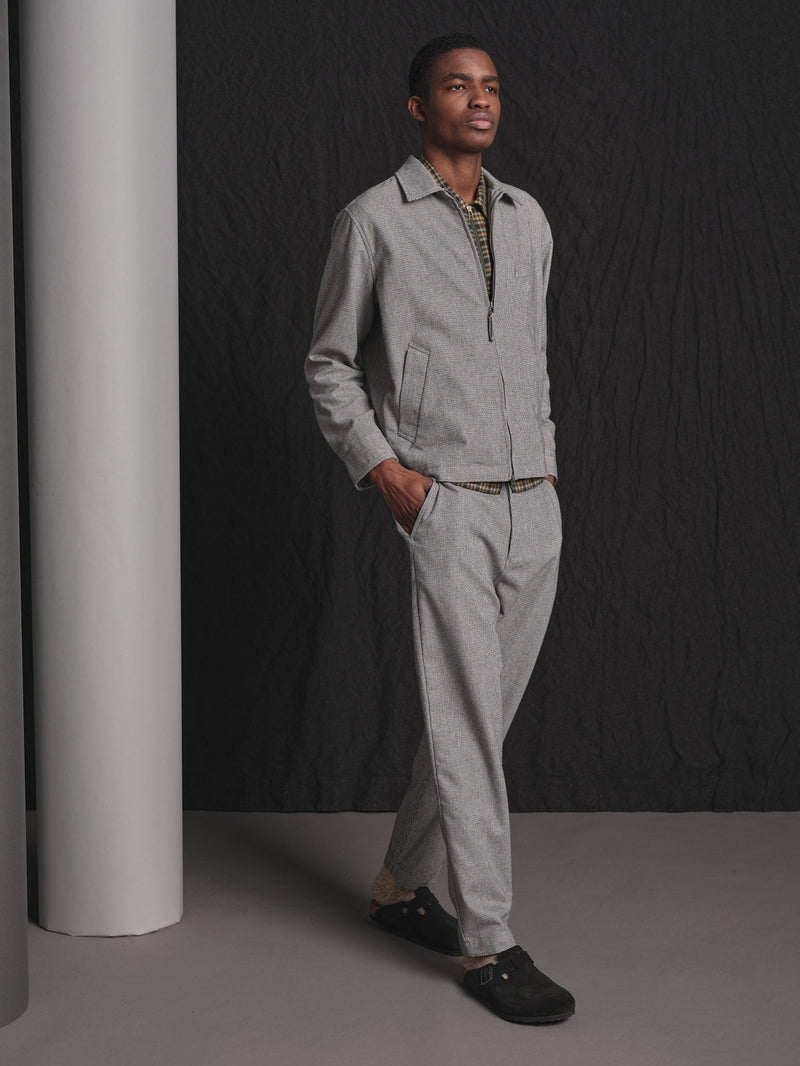 Man wearing a light gray suit standing against a dark background