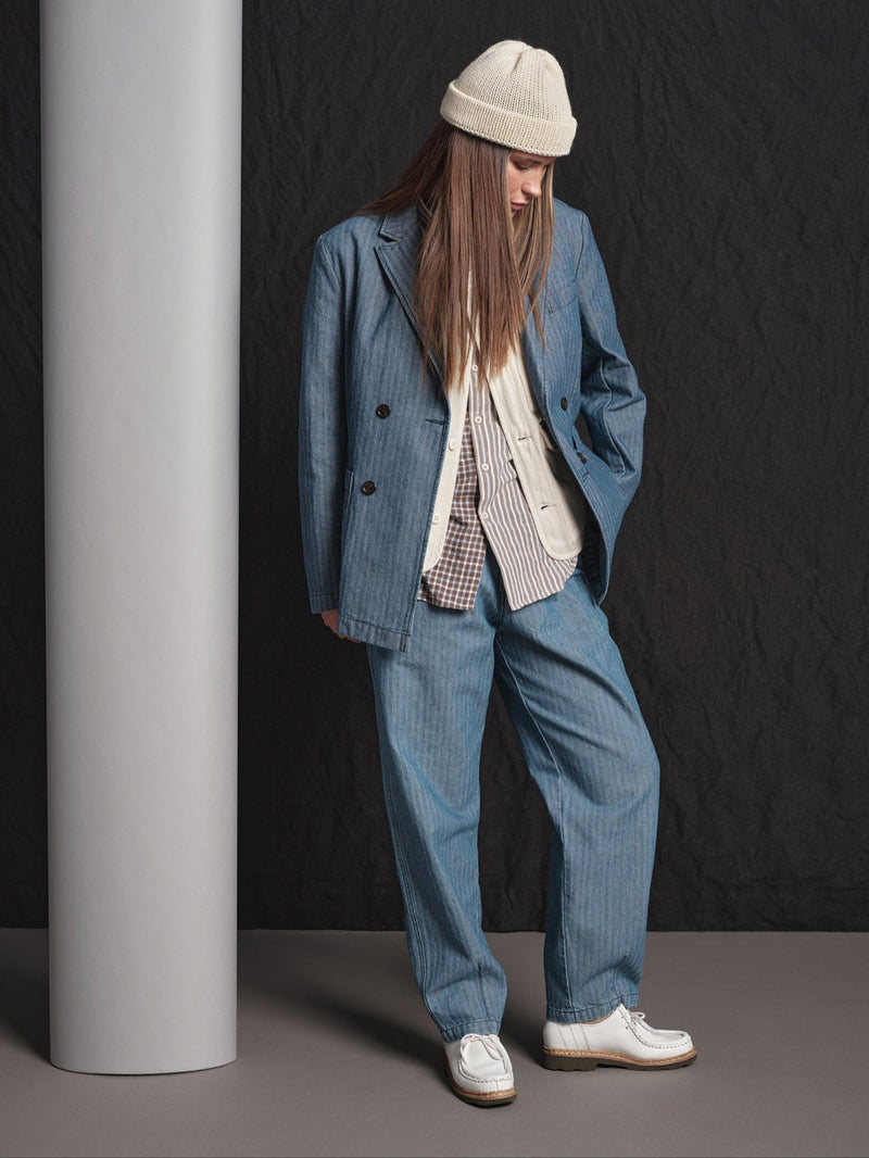 Person wearing a blue suit and white shoes against a black background