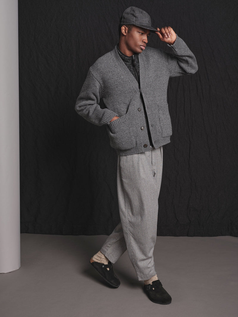 Man wearing a gray outfit with a cap against a black background